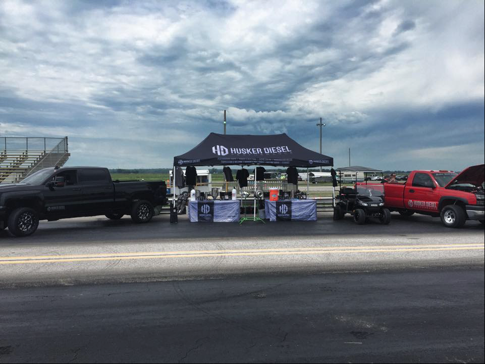 Husker Diesel trucks outside at event center with promotional tent